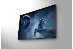 Canvastavla med LED-belysning 45x70 cm - Astronaut som sitter på en klippa och blickar ut mot jorden i rymden
