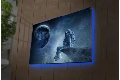 Canvastavla med LED-belysning - Astronaut som sitter på en klippa med jorden i bakgrunden